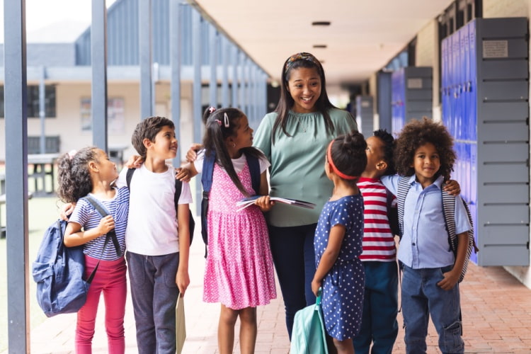 a teacher walks through the hallway of her school with a group of young students